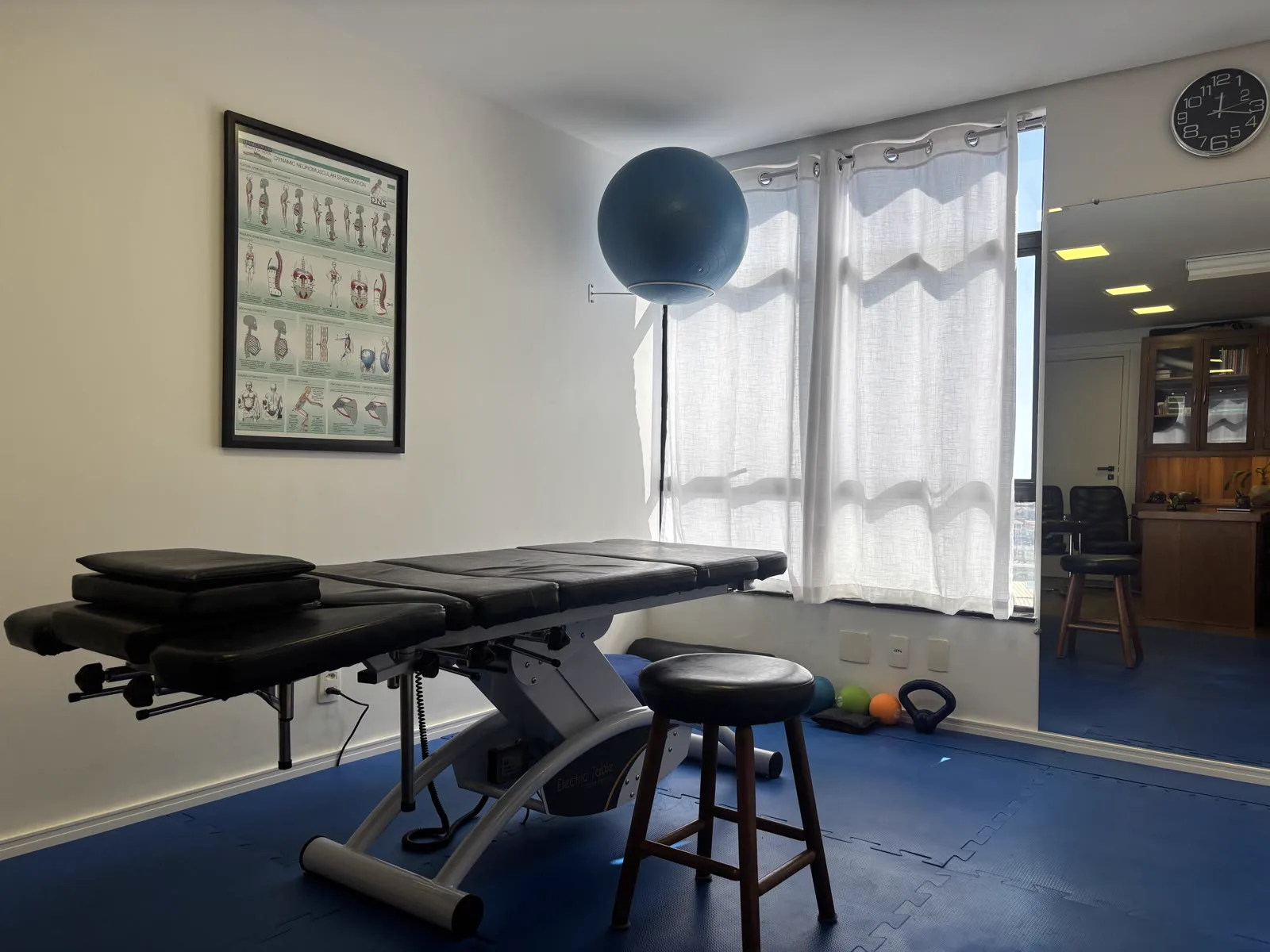 Sala de fisioterapia com bola suíça e maca de atendimento